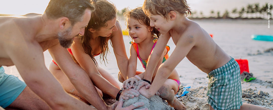 Familie mit Kindern spielt am Strand