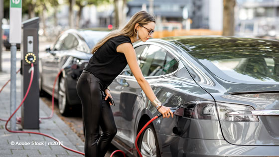 Frau ladet E-Auto auf