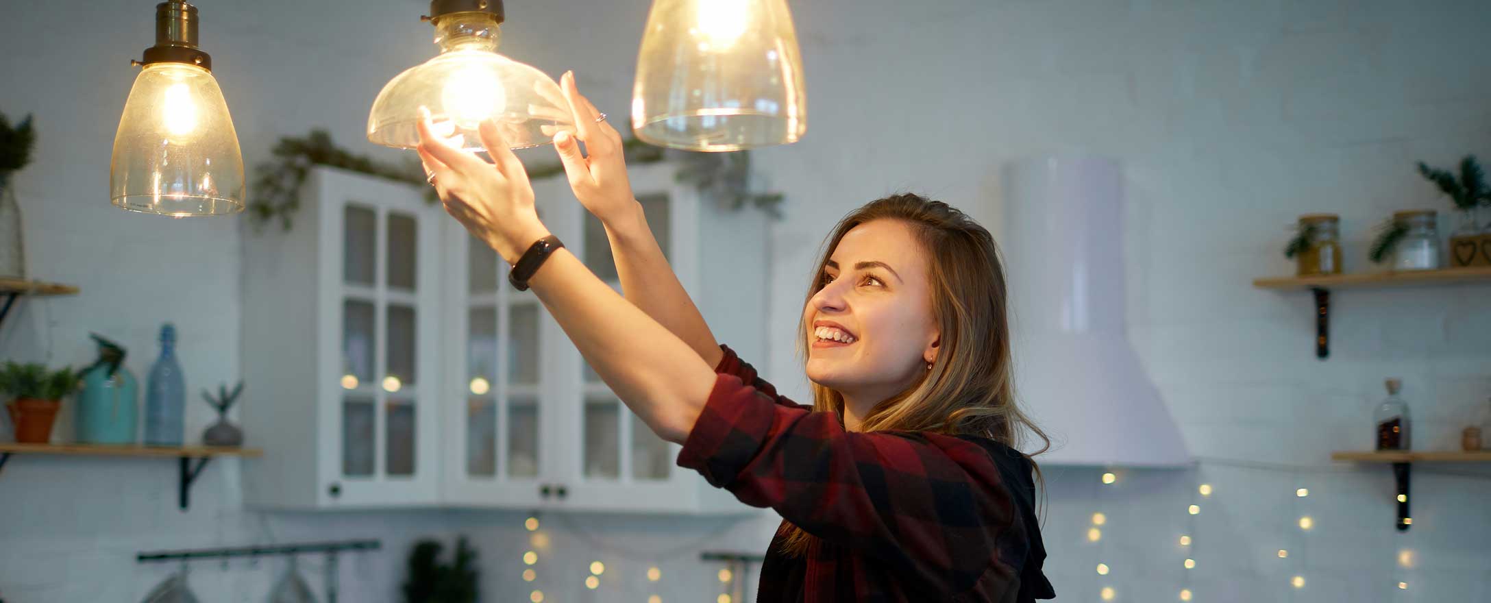 Junge Frau stellt Lampe in Küche ein